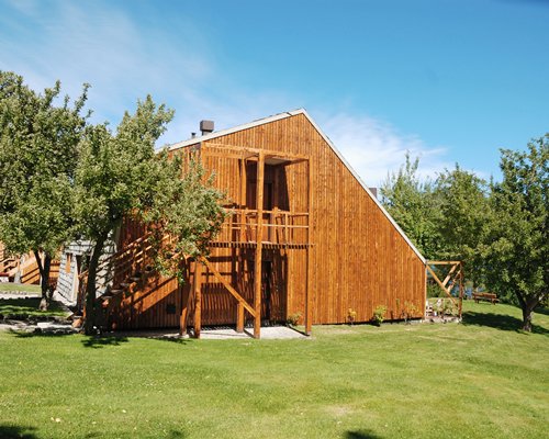 An exterior view of a treehouse surrounded by lawns and trees.
