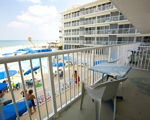 A balcony view of outdoor swimming pool alongside beach.