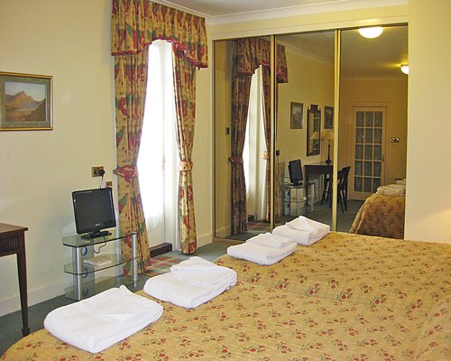 A well furnished bedroom with two double beds and a television.
