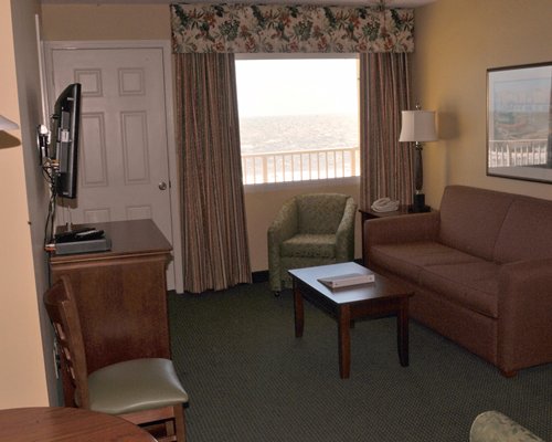 A well furnished living room with television double pull out sofa and a balcony.