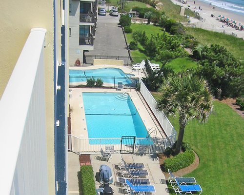 A top view of an outdoor swimming pool with chaise lounge chairs and landscaping.