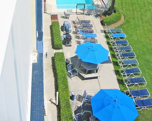An aerial view of outdoor swimming pool with sunshades and chaise lounge chairs.