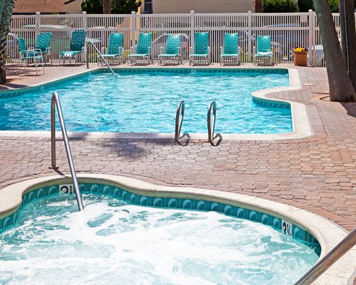 Outdoor swimming pool and kiddie pool with chaise lounge chairs.