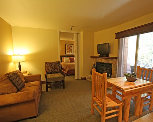 A well furnished bedroom dining and living area with a television.