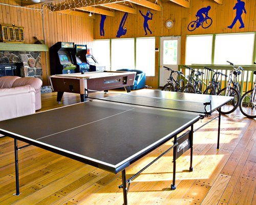 A wooden themed recreation room with table tennis bicycles and arcade games.