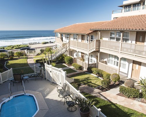 Scenic exterior view of Casa De La Playa resort with an outdoor hot tub alongside ocean.