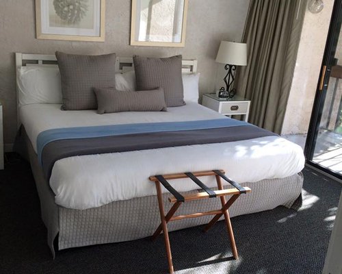 A well furnished bedroom with queen bed outdoor view and balcony.