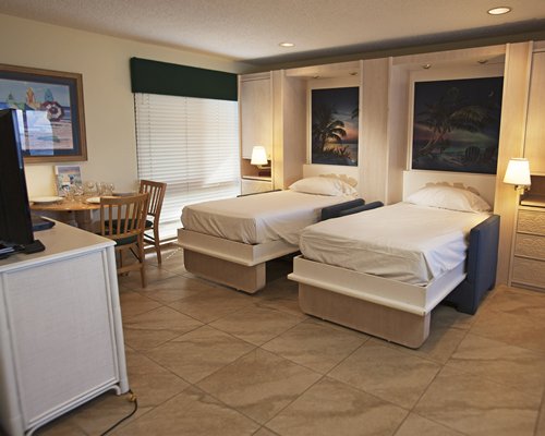 A well furnished bedroom with two twin beds and a television.