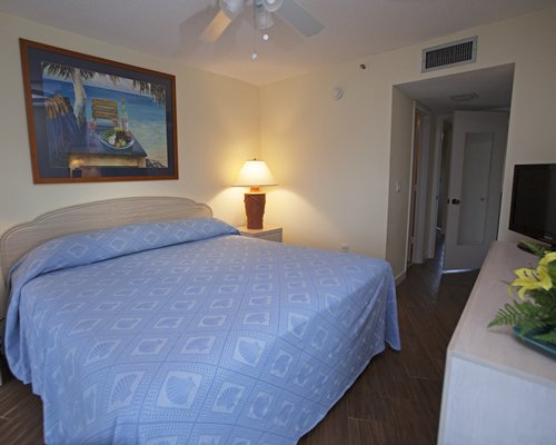 A well furnished bedroom with queen bed and television.