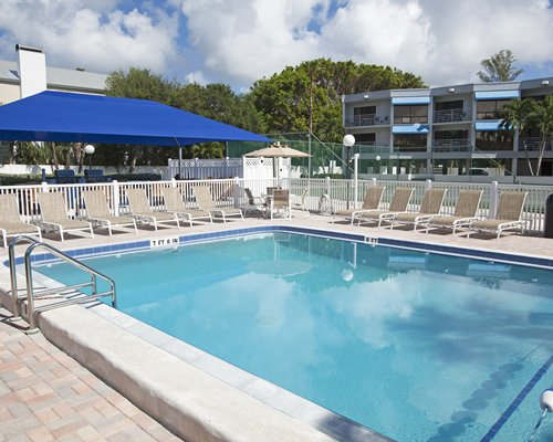 An outdoor swimming pool with chaise lounge chairs and sunshade.