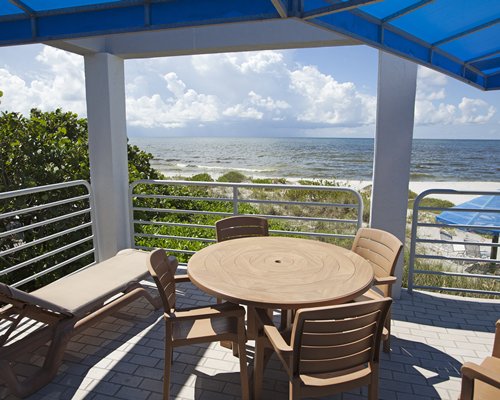 A dining area under a balcony alongside the ocean.