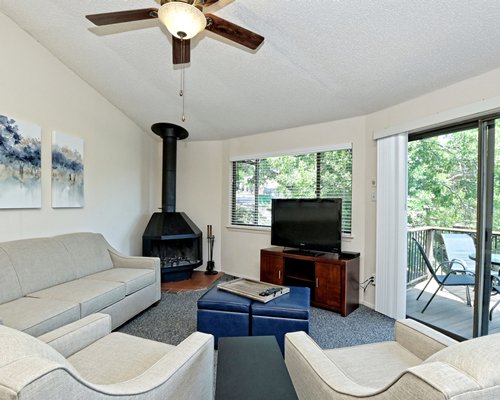 A well furnished living room with television fireplace and outside view.
