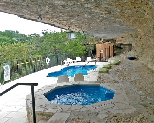 Outdoor hot tub with swimming pool and chaise lounge chairs.