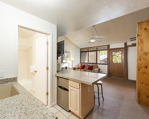 A well furnished living room with a television alongside a kitchen.
