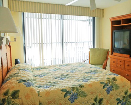 A well furnished bedroom with a queen bed and television.