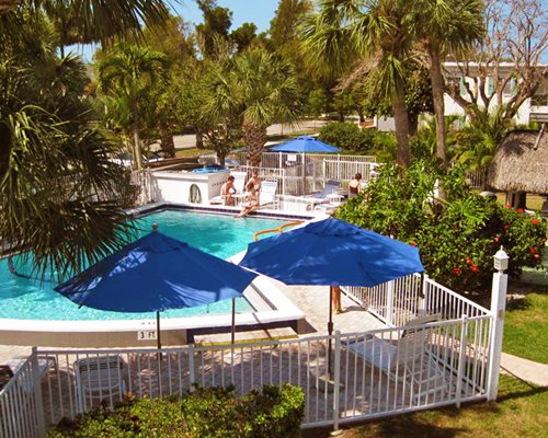 An outdoor swimming pool with chaise lounge chairs alongside sunshades and resort units.