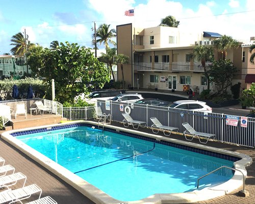 Scenic outdoor swimming pool with chaise lounge chairs alongside resort.