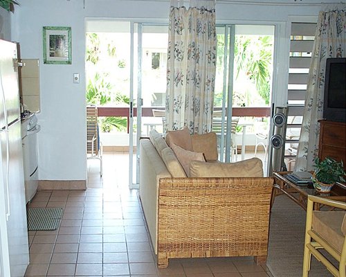 A well furnished living room with a balcony accompanied by patio chairs.