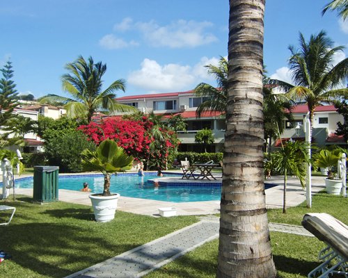 Scenic outdoor swimming pool with flowering shrubs alongside resort.