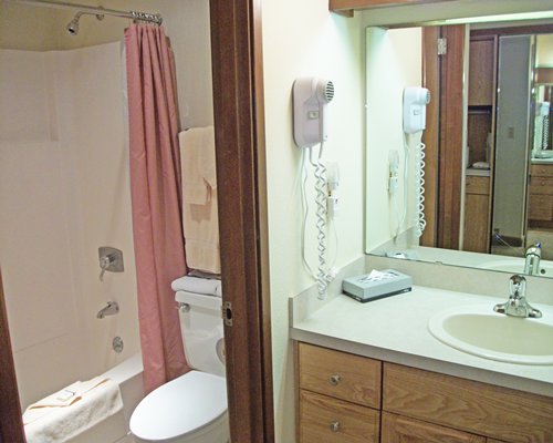 A bathroom with a bathtub shower and sink vanity.
