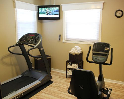 A well equipped indoor fitness center with a television.