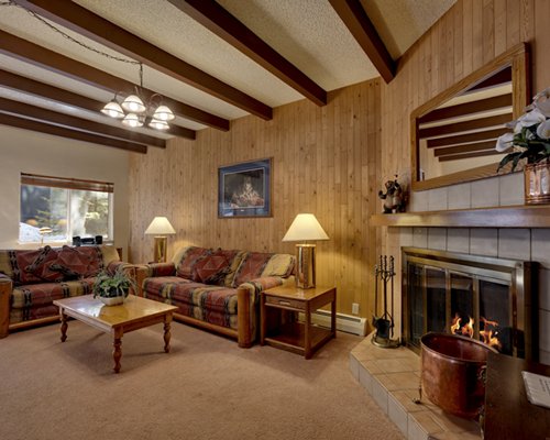 A well furnished living room with open plan kitchen dining area and fireplace.