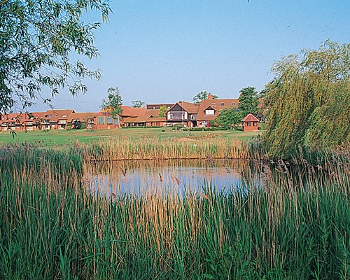 A scenic view of a barnham Broom Golf and Country Club alongside a pond.