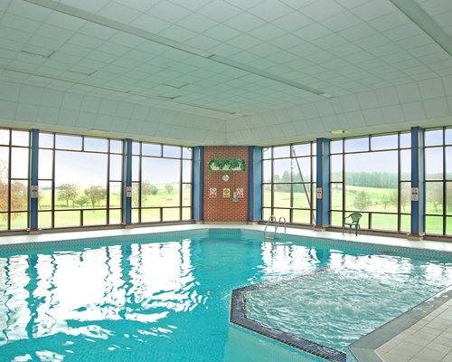 An indoor swimming pool with an outside view.