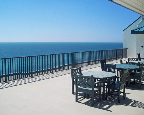 Balcony with patio tables chairs and ocean view.