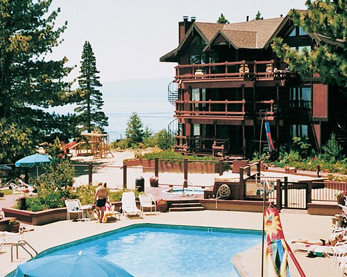 An exterior with outdoor pool chaise lounge chairs and lake view.