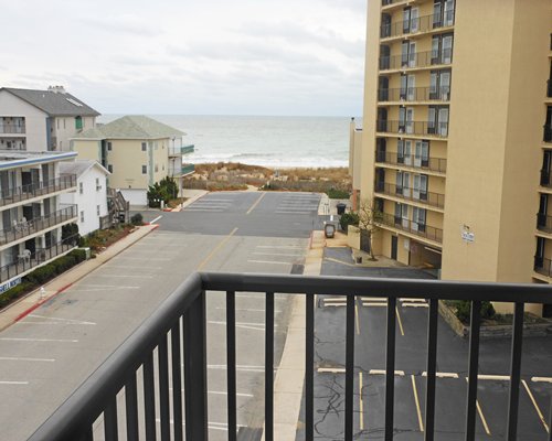 A balcony view of a multi story resort alongside a parking area.