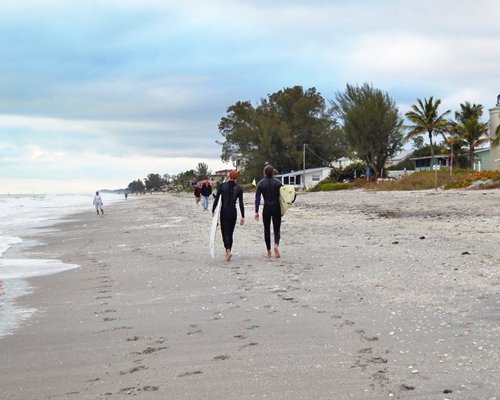 Two people walking along the beach holding surfboards.