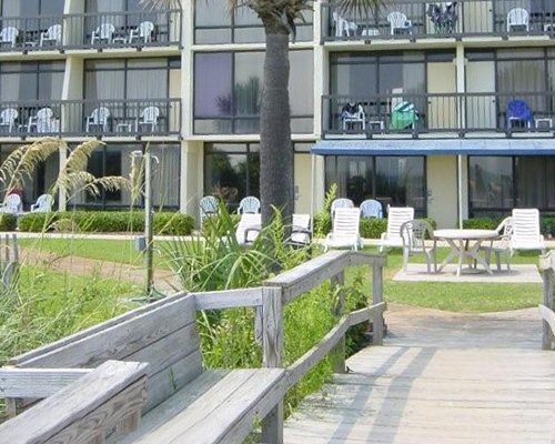 An exterior view of a multi story resort alongside patio furniture.