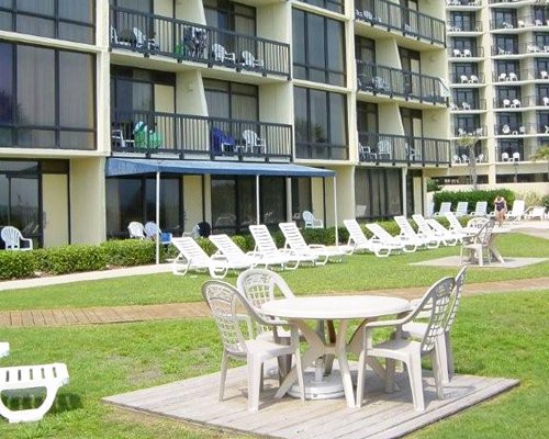 Scenic view of multiple unit balconies with picnic area and chaise lounge chairs and patio table.