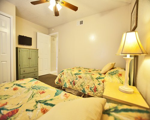 A well furnished bedroom with two beds and television.