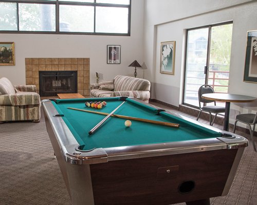 Indoor games room with pool table fireplace and outdoor view.