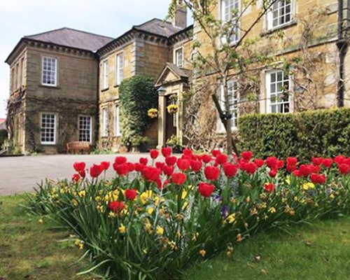 Ground view of Sutton Hall Timeshare Club Resort with flowering shrubs.