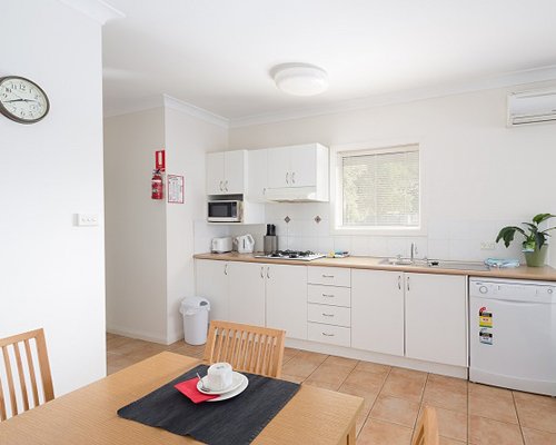 An open plan dining and kitchen area with a wooden table.