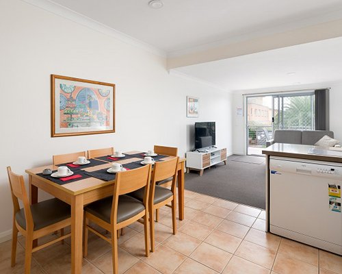 An open plan dining and living room with a television and an outdoor view.