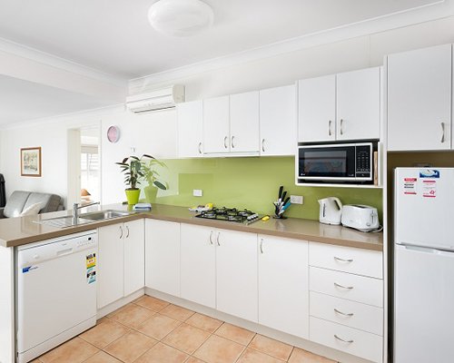 A well equipped modular kitchen with a microwave and refrigerator.