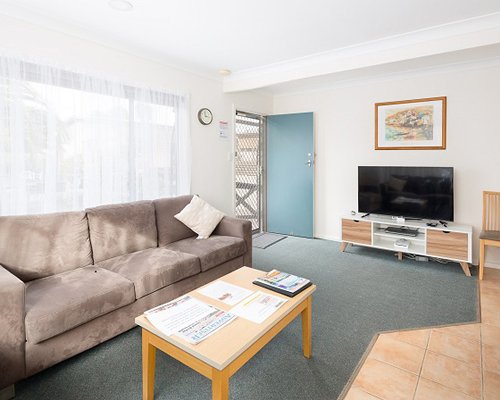 A well furnished living room with double pull out sofa and a television.