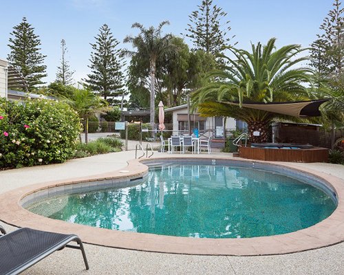 An outdoor swimming pool with patio chairs and landscape.