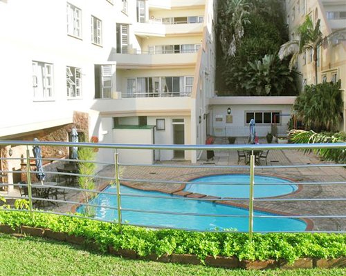 An outdoor swimming pool and hot tub with chaise lounge chairs alongside resort units.