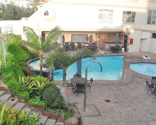 An outdoor swimming pool and hot tub with chaise lounge chairs.