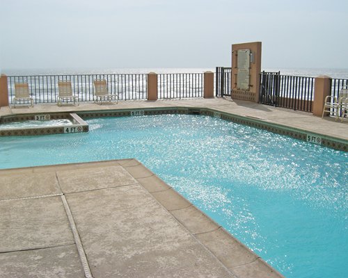 An outdoor pool with chaise lounge chairs along the shore.