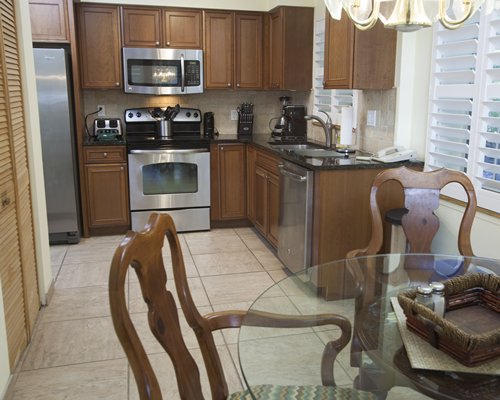 An open plan dining and kitchen area with a glass top table.