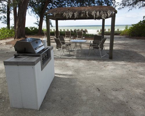 An outdoor barbecue grill with thatched sunshades.
