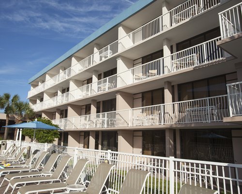 View of the multi story resort with chaise lounge chairs.