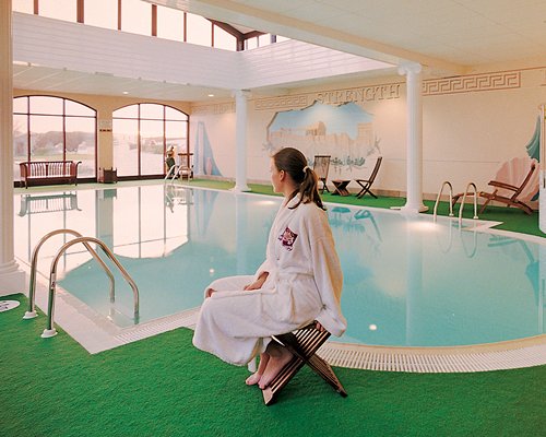 An indoor swimming pool with patio furniture and an outside view.