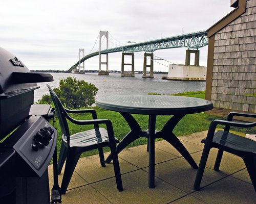 Scenic picnic area with barbeque grill and patio furniture facing the bridge.